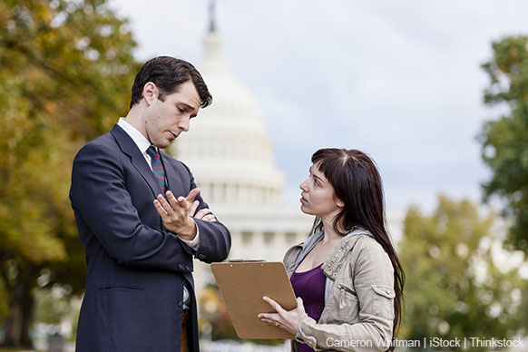 A photo shows a woman with a clipboard asking a man survey questions about his political views