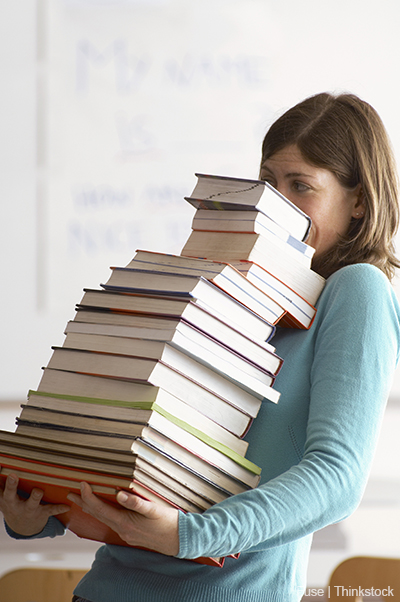 A photo shows a woman carrying a large stack of books